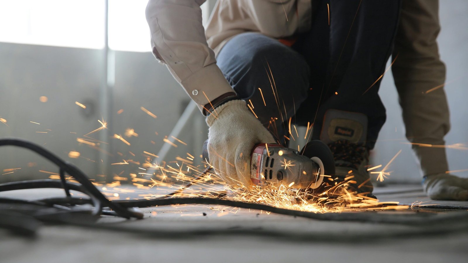 Construction A skilled industrial worker uses a grinder creating a burst of sparks indoors.
